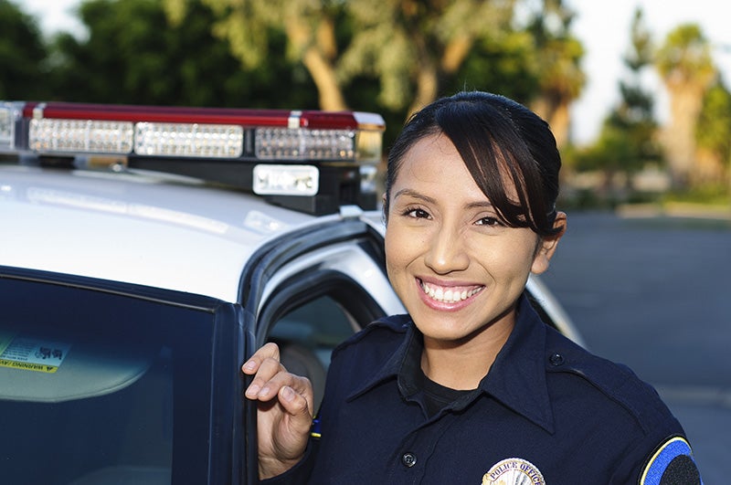 A group of female police officers, dressed in their crisp uniforms, are smiling warmly